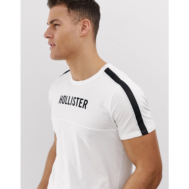 Camiseta blanca con logo en el pecho y cintas en las mangas de